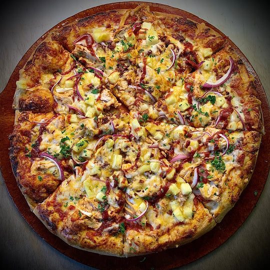 The BBQ chicken pizza. Golden brown crust and chicken, bright yellow pineapple, and purple red onion. 